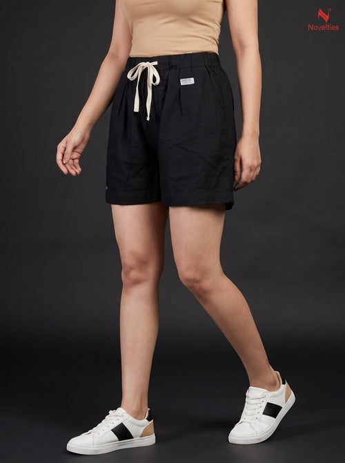 Model wearing Novelties® black pure cotton relaxed fit shorts with an elastic drawstring waist against a dark background