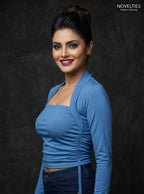 Model wearing a blue Novelties® square neck tube top with an attached long sleeve shrug overlay and ruched detailing.