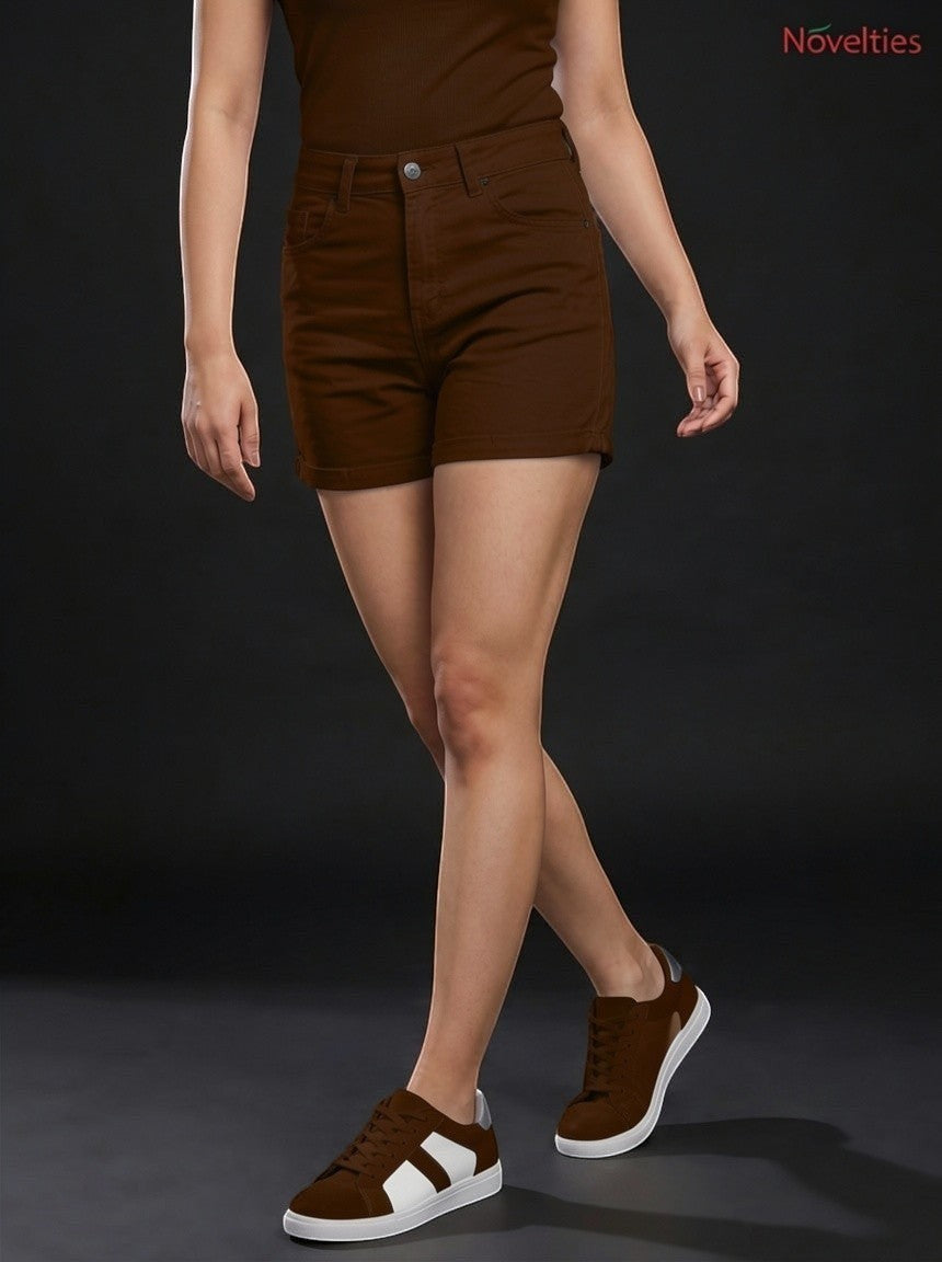Model wearing Novelties® high-rise brown denim shorts with a cuffed hem and button fly against a dark background.