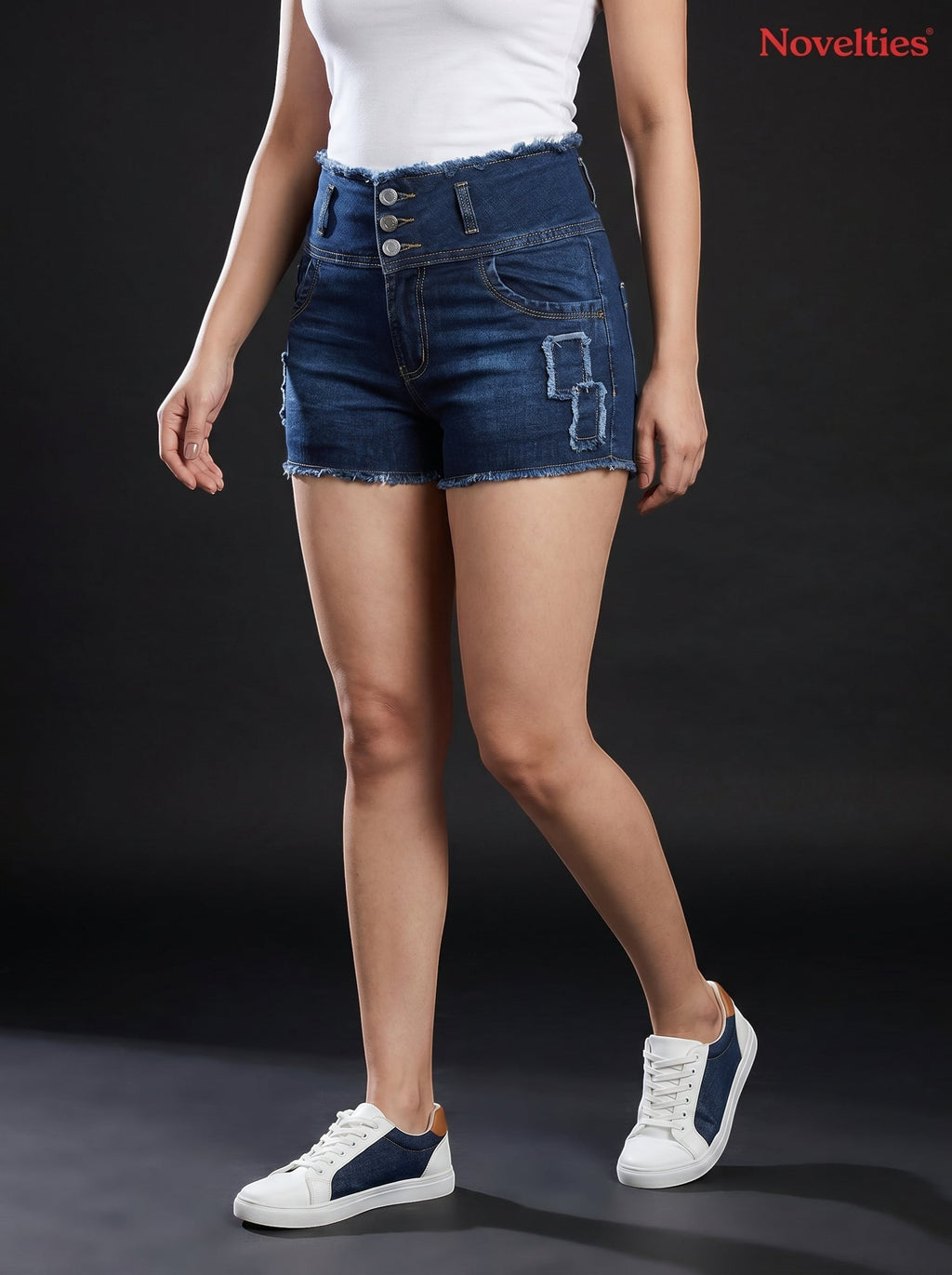 Model wearing Novelties® dark wash high-waisted denim shorts with a multi-button closure, frayed hem, and distressed detail.