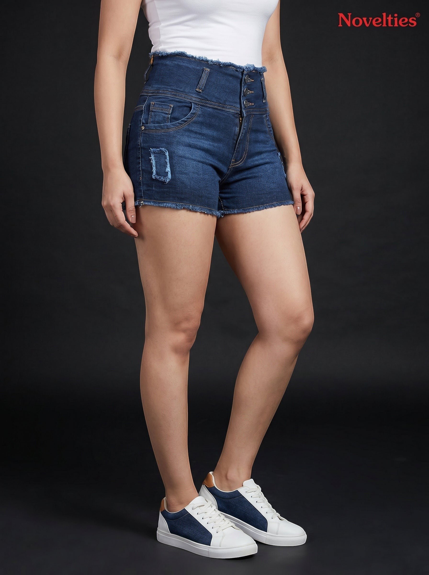 Model wearing Novelties® dark wash high-waisted denim shorts with a multi-button closure and frayed hem details.