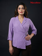 Model wearing a lavender Novelties® wrap-style top with notch lapels, three-quarter sleeves, and a side buckle detail.