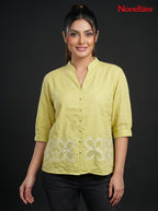 Model wearing a lime green Novelties® mandarin collar shirt with white cutwork floral embroidery at the hem.