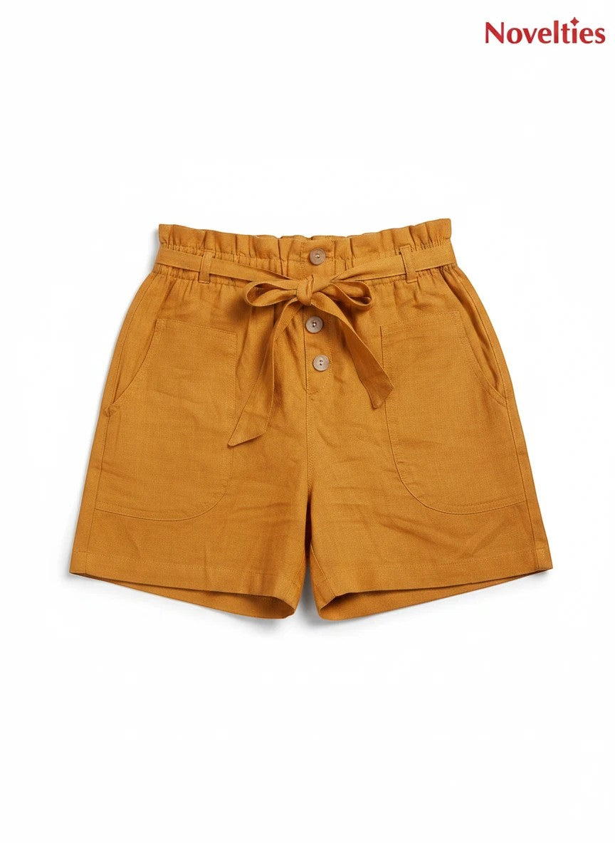 Novelties® mustard pure cotton shorts featuring a paperbag waist, self-tie belt, button placket, and side pockets.