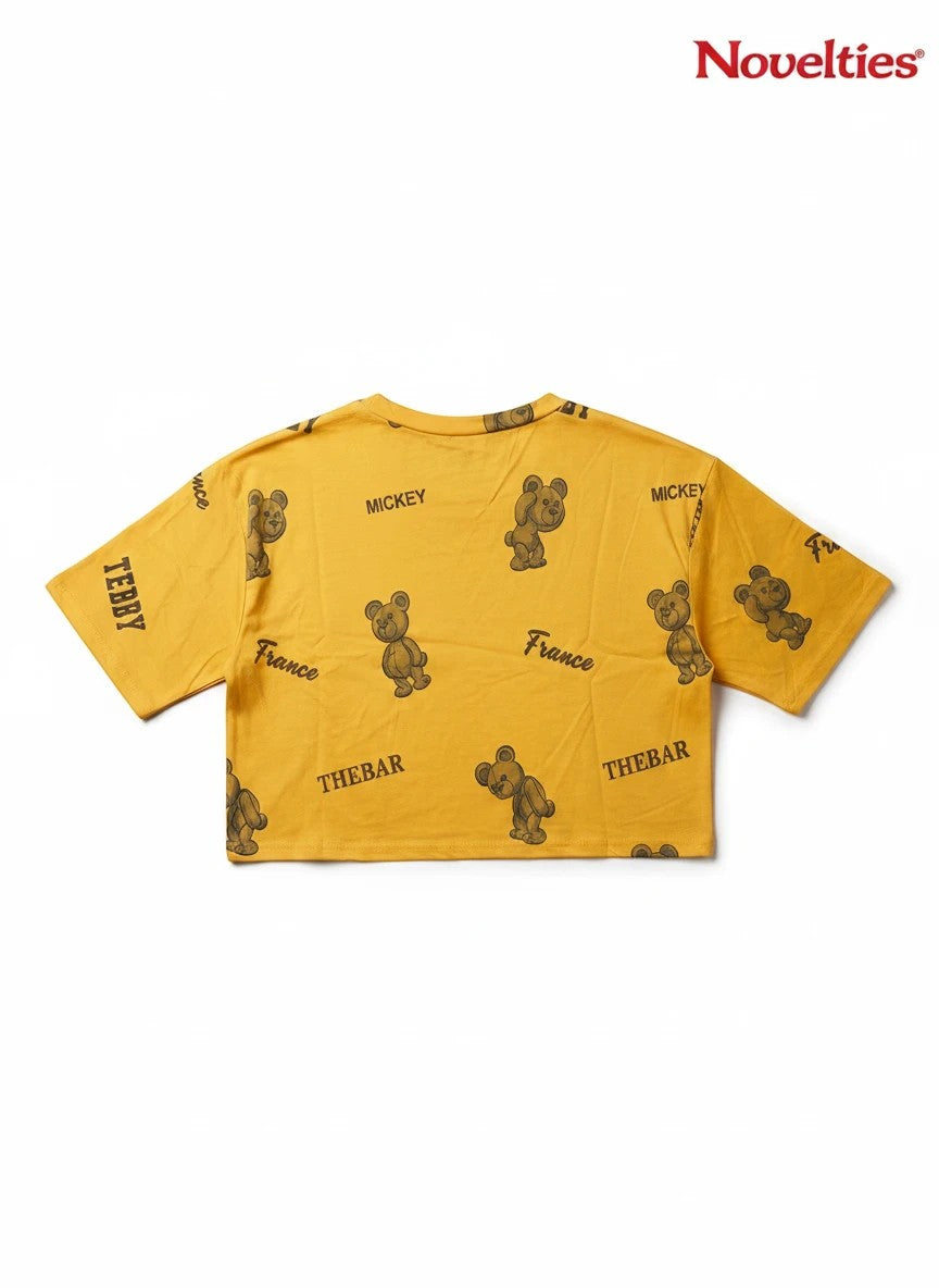 Novelties® mustard yellow crop top with all-over teddy bear graphic print and France typography.