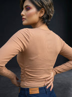 Model wearing a beige Novelties® ribbed long-sleeve crop top with a slim fit against a dark background.