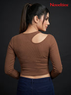 Model wearing a brown Novelties® ribbed long sleeve cropped top with an asymmetric shoulder cutout.