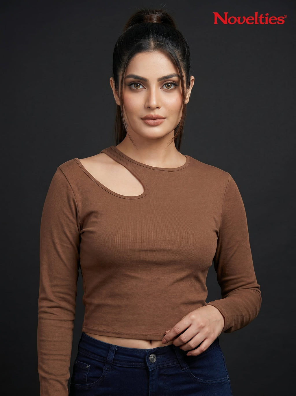 Model wearing a brown Novelties® ribbed long sleeve cropped top with an asymmetric shoulder cutout.