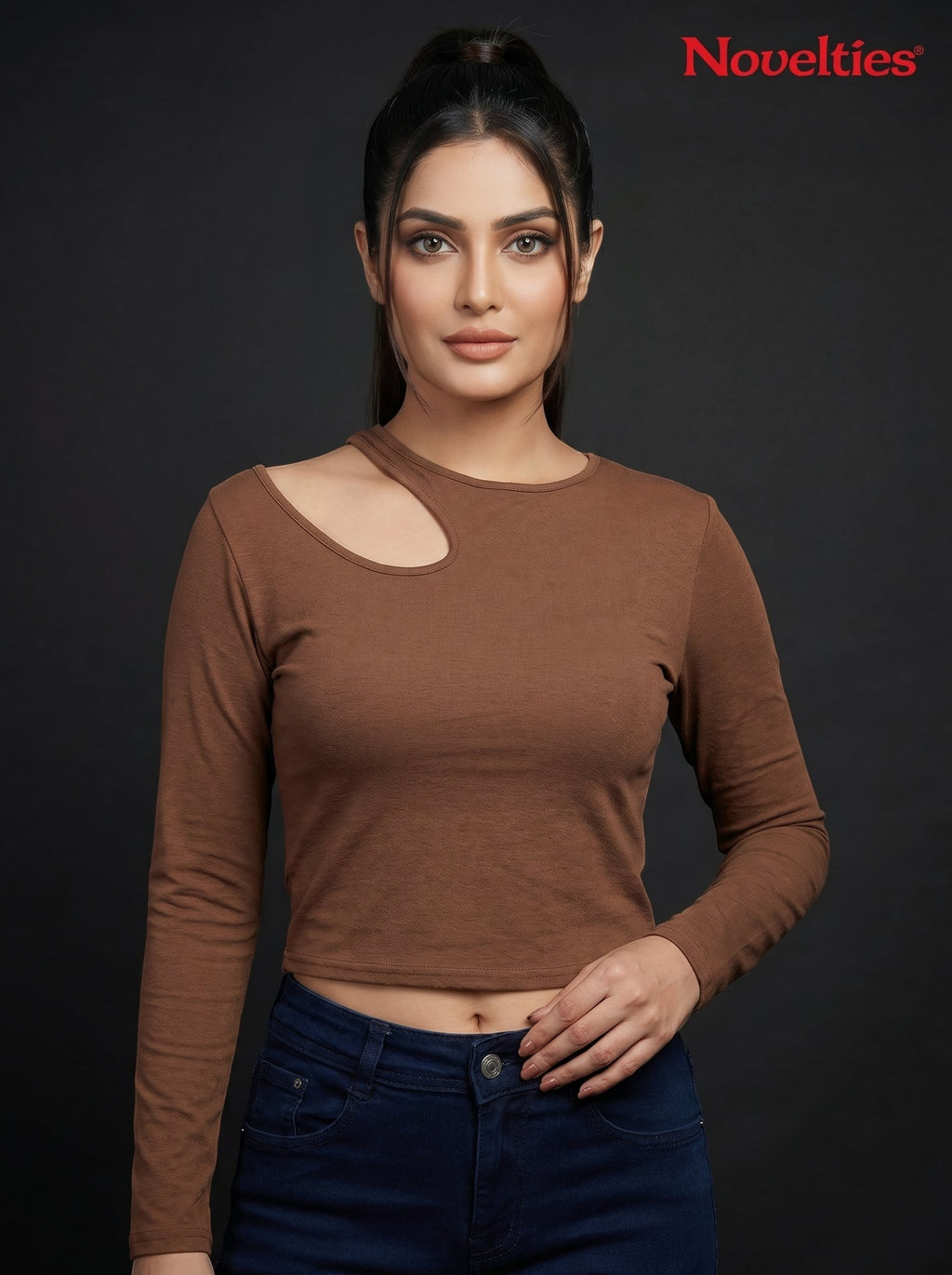 Model wearing a brown Novelties® ribbed long sleeve cropped top with an asymmetric shoulder cutout and crew neckline.
