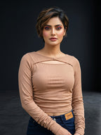 Model wearing a beige Novelties® ribbed crop top with long sleeves, boat neckline, and a twist-front chest cutout.