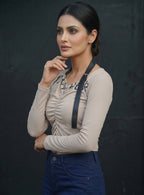 Model wearing a beige Novelties® ruched long-sleeve crop top with a black graphic print and detachable strap detail.