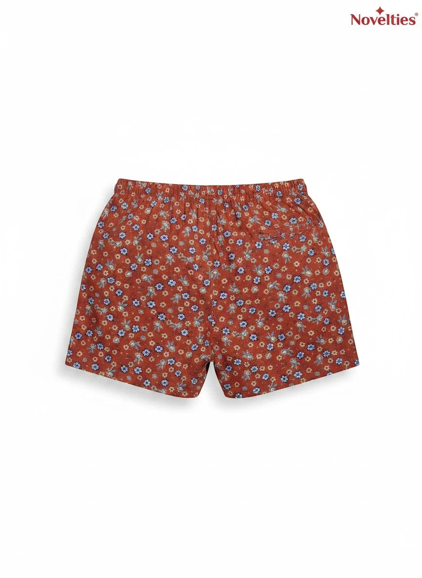 Novelties® rust floral print shorts with a ditsy pattern in blue, yellow, and green on a terracotta base.