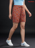 Model wearing Novelties® rust-toned ditsy floral print shorts with an elasticated drawstring waist on black background