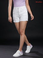 Model wearing Novelties® white high-rise denim shorts with a cuffed hem, paired with a lilac top and sneakers.