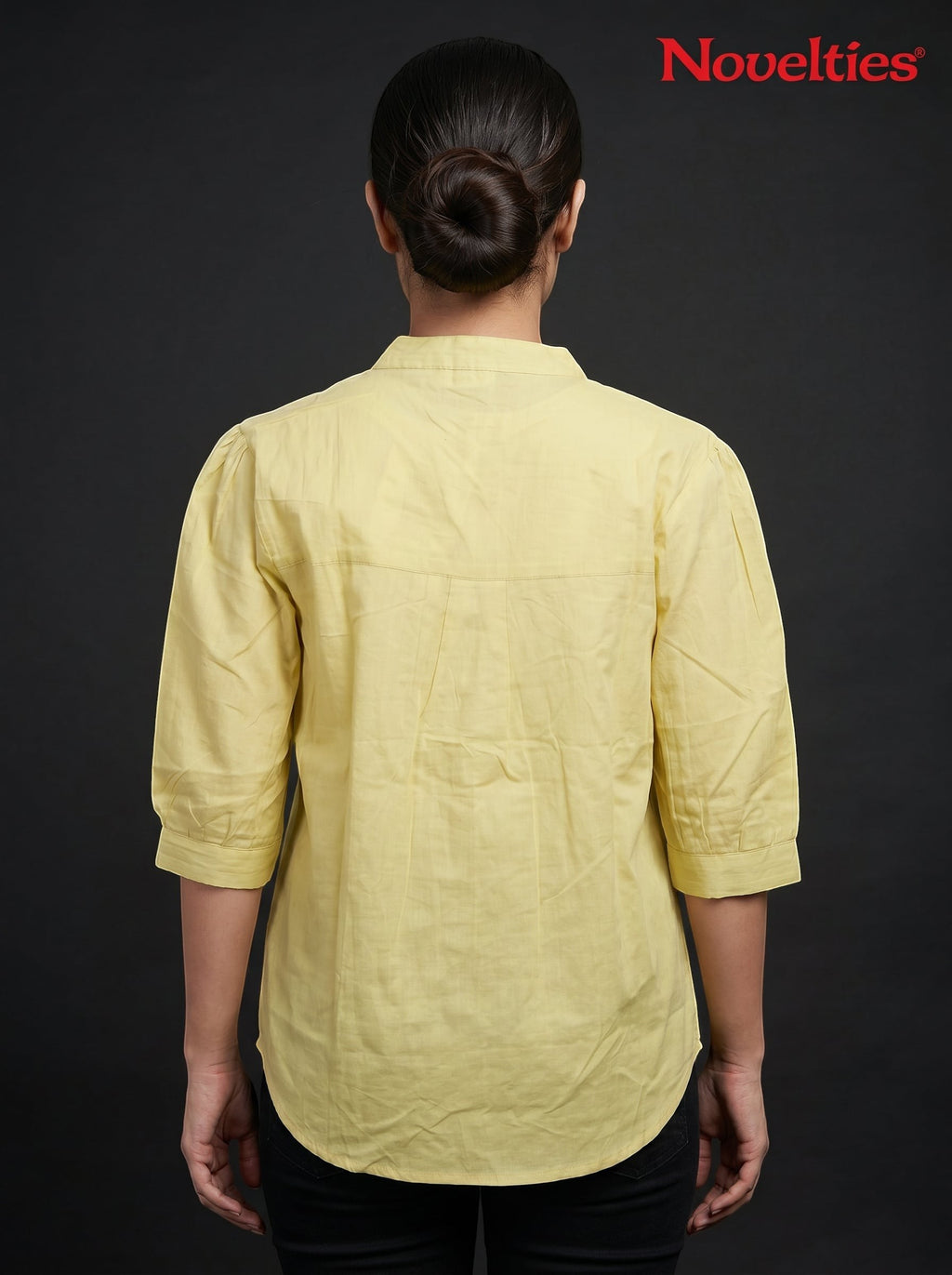 Back view of a woman wearing a yellow Novelties® mandarin collar shirt with three-quarter sleeves on a black background
