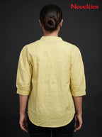 Back view of a woman wearing a yellow Novelties® mandarin collar shirt with three-quarter sleeves on a black background